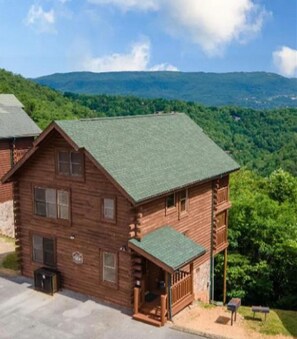 A wooden cabin with a green roof, a porch, and a view of a mountainous landscape. - Z - Tennessee Whiskey (Sevierville)