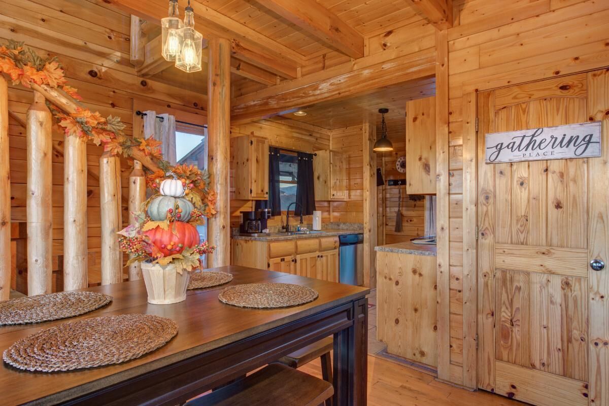 Un intérieur en bois comprenant une table à manger, un coin cuisine et un panneau indiquant « lieu de rencontre ».