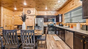 A wooden interior with a dining area, kitchen, and built-in appliances. - Rustic Modern Mountain Cabin (Pigeon Forge)