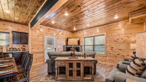 A cozy cabin interior with wooden walls, a dining area with a table and chairs, a sofa, and a fireplace. - Rustic Modern Mountain Cabin (Pigeon Forge)