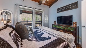 Un dormitorio con una cama, ventilador de techo, televisión y un letrero decorativo en la pared.