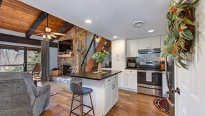 Una cocina moderna con una pared de acento de piedra, vigas de madera y una isla integrada.