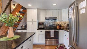 Una cocina con armarios blancos, electrodomésticos de acero inoxidable y una pared de acento de madera.