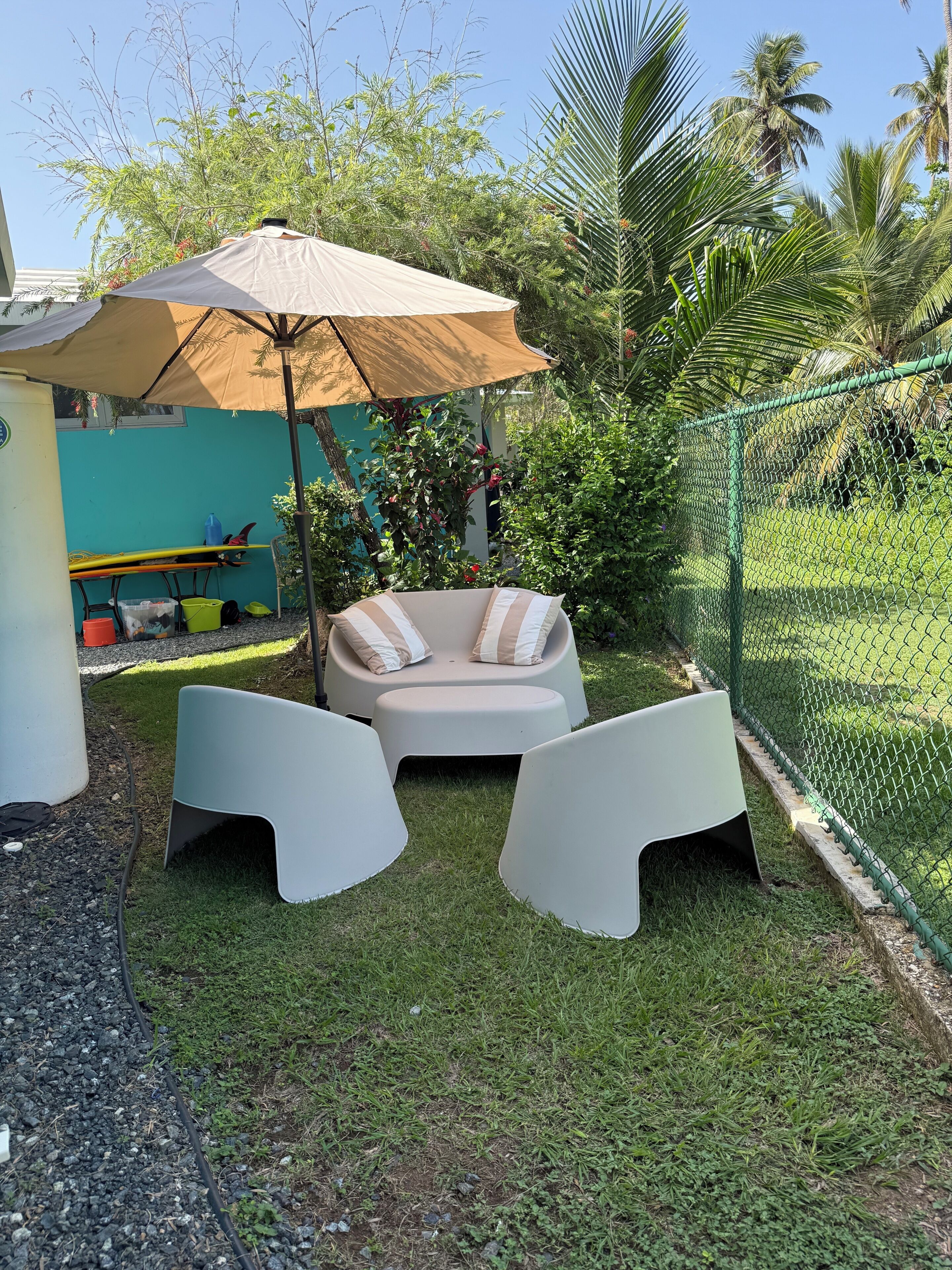 A patio area with a cushioned seating arrangement, a table, and an umbrella.