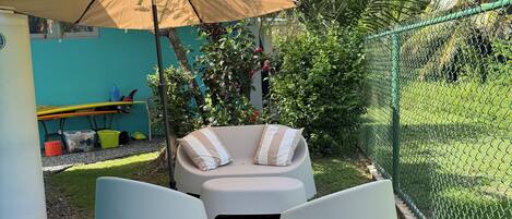 A patio area with a cushioned seating arrangement, a table, and an umbrella.