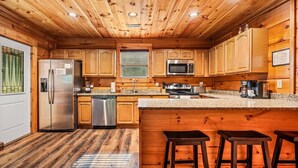 A wooden interior with a kitchen, bar area, and seating. - Mountain Getaway (Pigeon Forge)