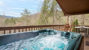 Un jacuzzi en una terraza con vistas a árboles y montañas.