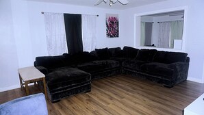 A living room with a sectional sofa, a small wooden bench, and a window with curtains. - Modern Heart of Hollywood (Hollywood)