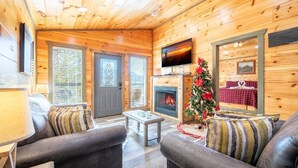 A cozy cabin interior with a fireplace, a television, and a Christmas tree. - Eagles Nest Hideaway (Cosby)