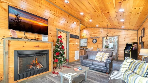 A log cabin interior with a fireplace, a television, a Christmas tree, and a sofa. - Eagles Nest Hideaway (Cosby)