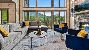 A modern living room with a sectional sofa, a coffee table, and a stone fireplace. - Revetta Retreat (Sevierville)