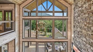 A multi-level wooden cabin with large windows, a deck, and a stone wall. - Revetta Retreat (Sevierville)