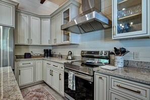 A modern kitchen with stainless steel appliances, white cabinetry, and a marble countertop. - Private Pond, Mountain Escape (Highlands)