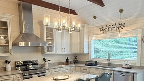 A modern kitchen with a large island, pendant lighting, and a view of the outdoors. - Private Pond, Mountain Escape (Highlands)