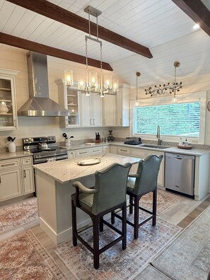 A modern kitchen with a large island, pendant lighting, and a view of the outdoors. - Private Pond, Mountain Escape (Highlands)
