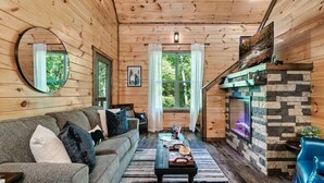 A cozy cabin interior with a wooden interior, a sofa, a fireplace, and a mirror. - Bear Up There Cabin (Sevierville)
