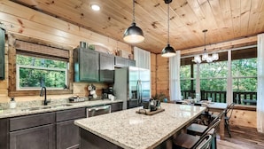 A modern kitchen with granite countertops, stainless steel appliances, and a large island. - Bear Up There Cabin (Sevierville)