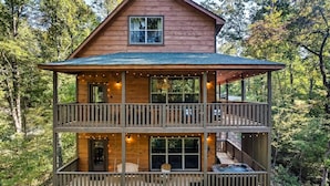 A multi-level wooden cabin with balconies, large windows, and a hot tub. - Bear Up There Cabin (Sevierville)