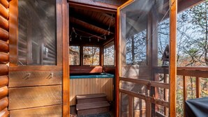 Een houten blokhut met een glazen deur naar een zone met een jacuzzi.
