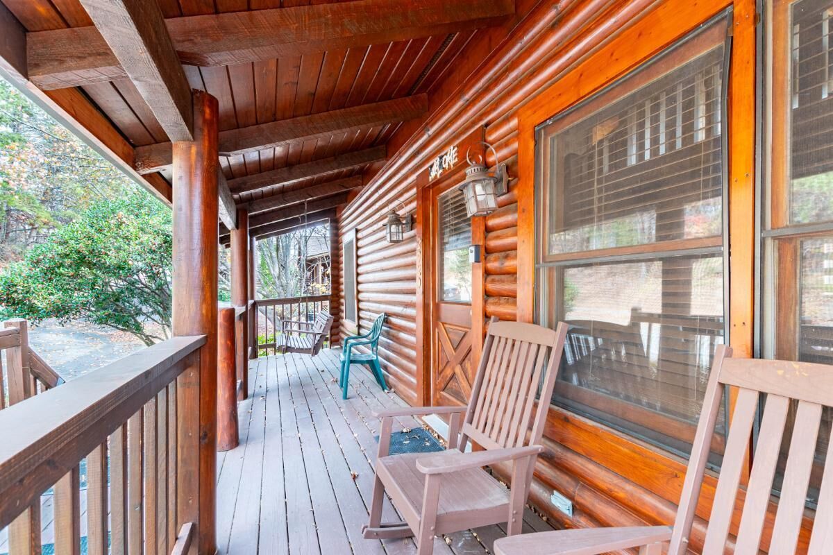 Eine Holzhütte mit Veranda, Holzstühlen und einem Fenster.