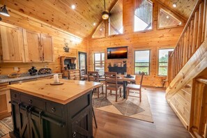 A wooden cabin interior with a kitchen, dining area, and a fireplace. - Z - Heavenly Views Hideaway (Sevierville)