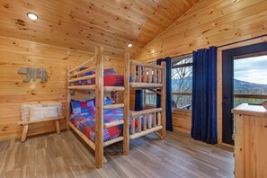 A wooden cabin with bunk beds, a bench, and a view of the outdoors. - Pine Haven Cabin (Sevierville)