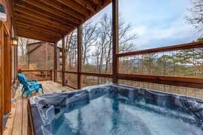 A hot tub on a wooden deck with a view of trees and a building. - Pine Haven Cabin (Sevierville)