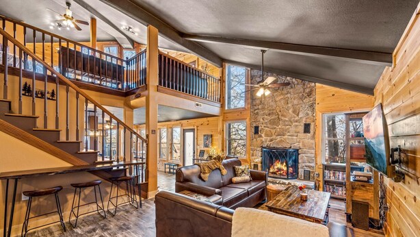 A multi-level wooden cabin with a fireplace, a staircase, and a cozy seating area. - Z - Honey Bear Treehouse (Gatlinburg)