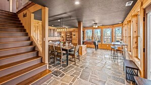 A wooden interior with a stone floor, a dining area, and a staircase. - Z - Honey Bear Treehouse (Gatlinburg)