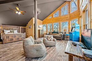 Ein geräumiger Loft-Raum mit einem großen Bett, zwei Sesseln, einem Holzesstisch und einem Fernseher.
