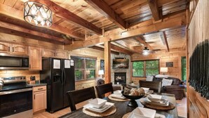 A wooden cabin interior with a kitchen, dining area, and fireplace. - Awesome Adventures (Sevierville)