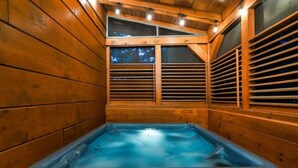 A hot tub in a wooden cabin with a sloped ceiling and wooden walls. - Awesome Adventures (Sevierville)