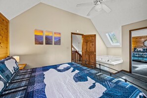 Ein Schlafzimmer mit einem großen Bett, einem Oberlicht, einer Holztür und Blick auf eine Whirlwanne.