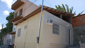 Un edificio de dos plantas con techo plano, un balcón pequeño y una reja de seguridad.