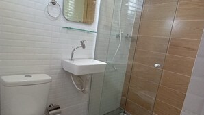 Un baño con inodoro, lavamanos y ducha con mampara de vidrio.