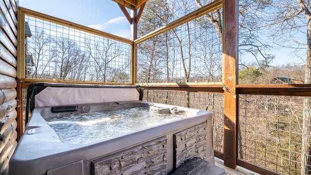 A hot tub in a wooden cabin with a view of trees. - Magical Meadow (Sevierville)