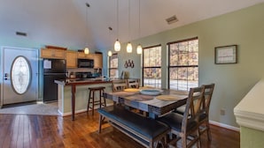 A kitchen with wooden cabinets, a refrigerator, and a dining area with a table and benches. - Blue Mist Vista (Gatlinburg)