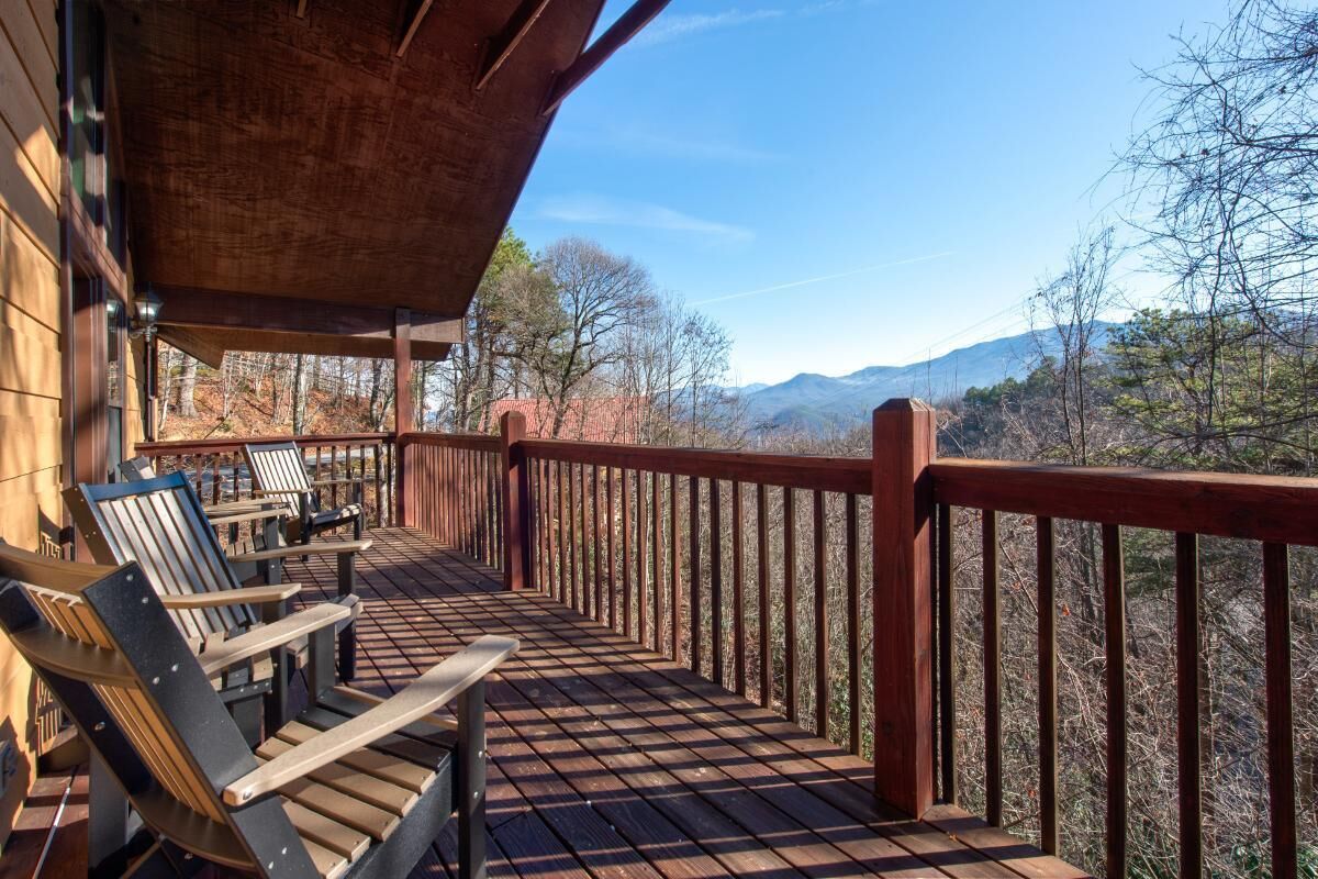Eine Holzterrasse mit Stühlen, einem Tisch und Blick auf Berge.