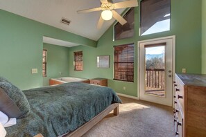 A bedroom with a bed, a dresser, a window with blinds, a door leading outside, and a ceiling fan. - Blue Mist Vista (Gatlinburg)