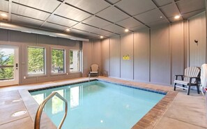 An indoor swimming pool with a view of the outdoors, a caution sign, and Adirondack chairs. - Misty Shadows (Sevierville)