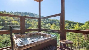 Ein Whirlpool auf einer Holzterrasse mit Blick auf eine bewaldete Landschaft.