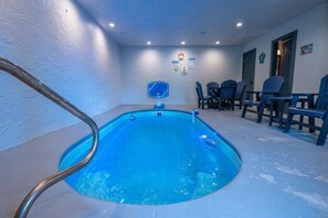 A swimming pool with a metal ladder, surrounded by chairs and tables, with a ceiling fan and wall-mounted signs. - Splash N' Love Shack (Sevierville)