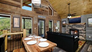 A wooden cabin interior with a dining table set, a fireplace, and a sofa. - Splash N' Love Shack (Sevierville)