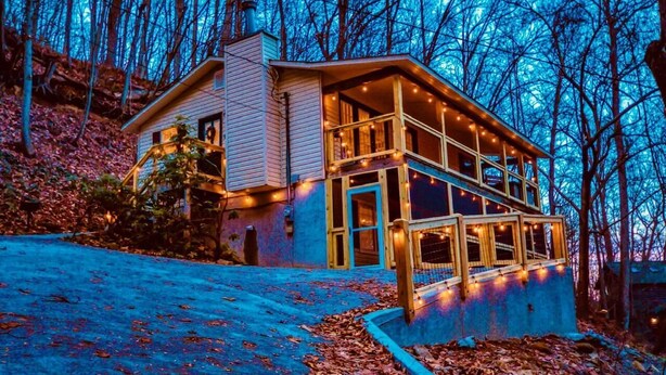 A two-story house with a porch, surrounded by trees and covered in fallen leaves. - Smoky Mountain Game Den (Gatlinburg)