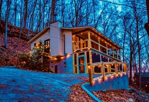 A two-story house with a porch, surrounded by trees and covered in fallen leaves. - Smoky Mountain Game Den (Gatlinburg)
