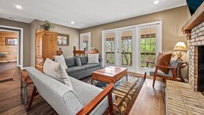 A living room with a sofa, armchair, coffee table, wooden cabinet, and a fireplace. - Smoky Mountain Game Den (Gatlinburg)