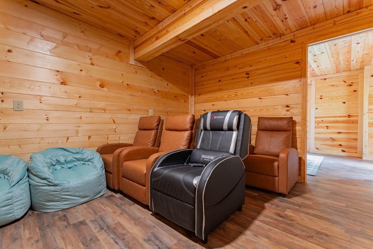 Eine Holzhütte mit zwei Ledersesseln, einem Massagesessel und zwei Sitzsäcken.