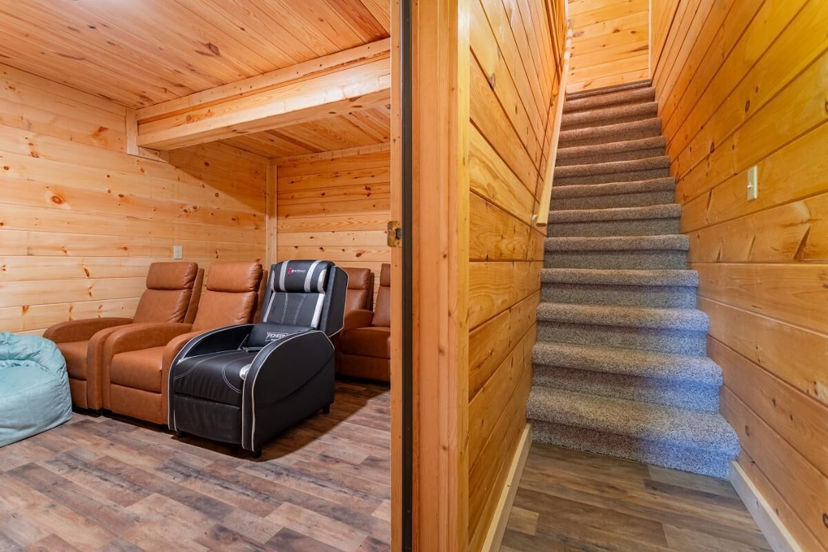 A wooden cabin interior with a massage chair, a sofa, and a staircase.