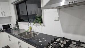 Una cucina moderna con mobili bianchi, un lavello doppio, un piano cottura a gas e una finestra vista.
