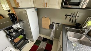 Een kleine keuken met een koelkast, magnetron, spoelbak en een koffiezetapparaat op een karretje.